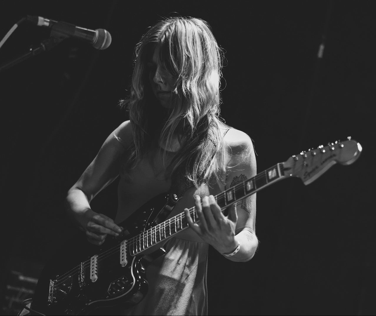 Person playing guitar on stage with a microphone in a dark setting